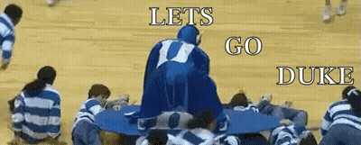 A Group Of People Are Sitting Around A Table With The Words Let 'S Go Duke On The Bottom GIF