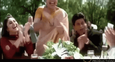 A Group Of People Are Sitting At A Table Clapping And Laughing GIF