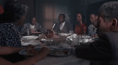 A Group Of People Are Sitting At A Table Eating Food . GIF