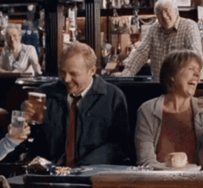 A Group Of People Are Sitting At A Table In A Bar Drinking Beer And Laughing . GIF
