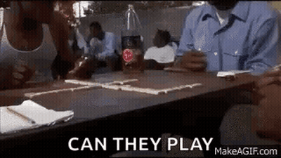 A Group Of People Are Sitting At A Table Playing Dominoes With A Coca Cola Bottle In The Background . GIF
