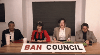 A Group Of People Are Sitting At A Table With A Sign That Says Ban Council GIF