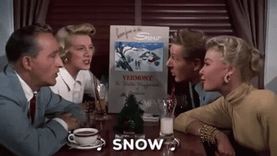 A Group Of People Are Sitting At A Table With A Sign That Says `` Snow '' . GIF