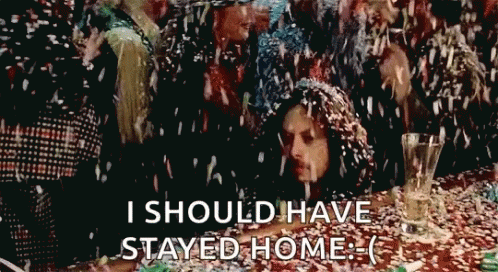A Group Of People Are Sitting At A Table With Confetti Falling On Them And The Words " I Should Have Stayed Home " GIF
