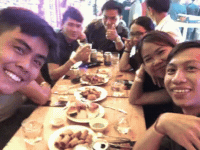 A Group Of People Are Sitting At A Table With Plates Of Food And Drinks GIF