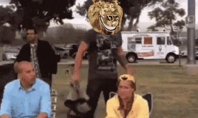 A Group Of People Are Sitting In A Park With A Lion 'S Head Above Them GIF