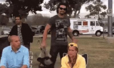 A Group Of People Are Sitting In A Park With A White Truck In The Background . GIF