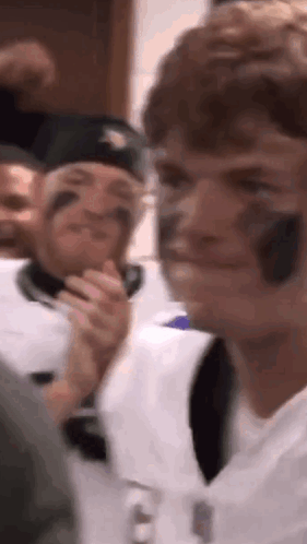 A Group Of People Are Sitting In A Room And One Of Them Is Wearing A Baseball Helmet On His Face . GIF