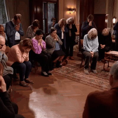 A Group Of People Are Sitting In A Room And Praying GIF