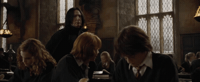 A Group Of People Are Sitting In A Room With A Man In A Black Suit Standing Behind Them GIF