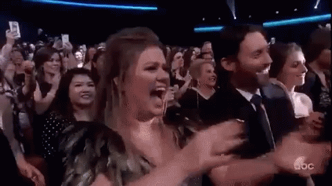 A Group Of People Are Sitting In A Stadium Watching A Concert And Applauding . GIF