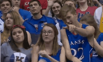 A Group Of People Are Sitting In A Stadium Wearing Kansas Shirts GIF