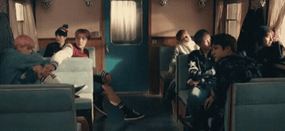 A Group Of People Are Sitting In A Train Car Talking To Each Other . GIF