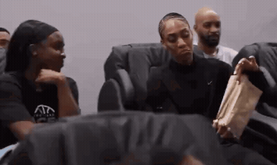 A Group Of People Are Sitting In Chairs Talking To Each Other . GIF