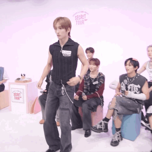 A Group Of People Are Sitting In Front Of A Sign That Says Secret Tour On It GIF