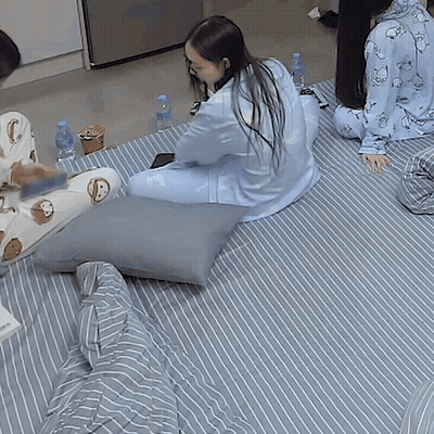 A Group Of People Are Sitting On A Bed With Pillows And Bottles Of Water . GIF