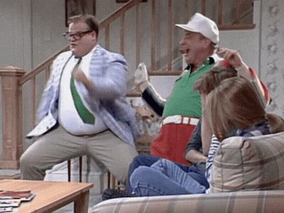 A Group Of People Are Sitting On A Couch And One Man Is Standing On A Chair GIF
