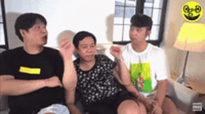 A Group Of People Are Sitting On A Couch Talking To Each Other In A Living Room . GIF