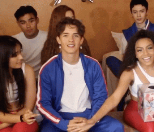 A Group Of People Are Sitting On A Couch With A Man In A Blue Jacket . GIF