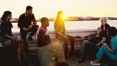 A Group Of People Are Sitting On A Dock Near A Body Of Water GIF
