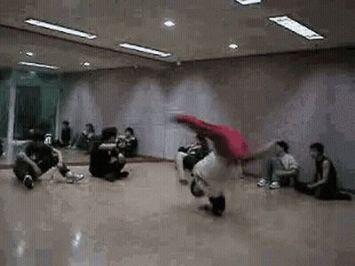 A Group Of People Are Sitting On The Floor In A Dance Studio Watching A Person Do A Trick . GIF