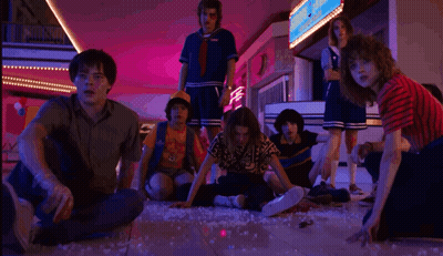 A Group Of People Are Sitting On The Floor In A Mall Looking At Something . GIF