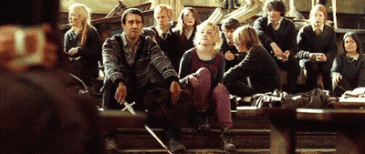 A Group Of People Are Sitting On The Steps Of A Building And One Of Them Is Holding A Sword GIF
