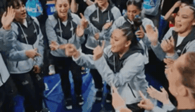 A Group Of People Are Standing Around A Basketball Court Giving High Fives . GIF