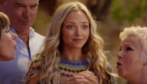 A Group Of People Are Standing Around A Blonde Woman Who Is Crying . GIF