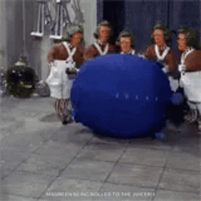 A Group Of People Are Standing Around A Blueberry . GIF