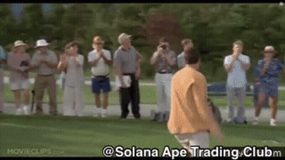 A Group Of People Are Standing Around A Golf Course Watching A Man Swing A Golf Club . GIF