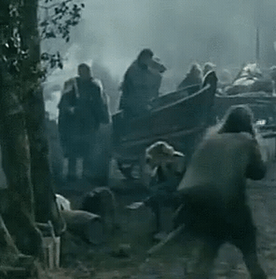 a group of people are standing around a horse drawn carriage in the woods .