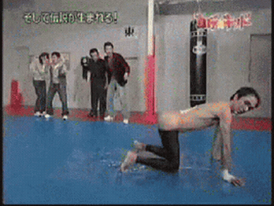 A Group Of People Are Standing Around A Man On His Knees In A Gym GIF