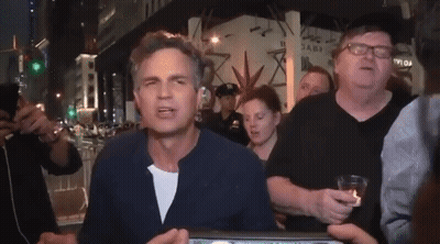 A Group Of People Are Standing Around A Man Wearing Glasses And A Hat That Says ' Abercrombie ' On It GIF
