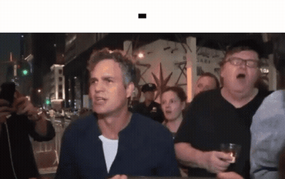 A Group Of People Are Standing Around A Man Who Is Holding A Glass . GIF