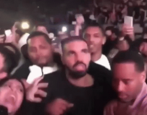 A Group Of People Are Standing Around A Man With A Beard In A Crowd . GIF