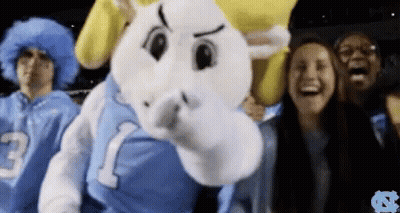 A Group Of People Are Standing Around A Mascot Wearing A Jersey With The Number 1 On It GIF