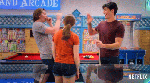 A Group Of People Are Standing Around A Pool Table In An Arcade With A Netflix Logo In The Corner . GIF