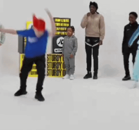 A Group Of People Are Standing Around A Sign That Says Sturdy GIF