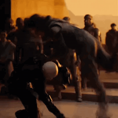 A Group Of People Are Standing Around A Statue Of A Man In A Black Suit . GIF
