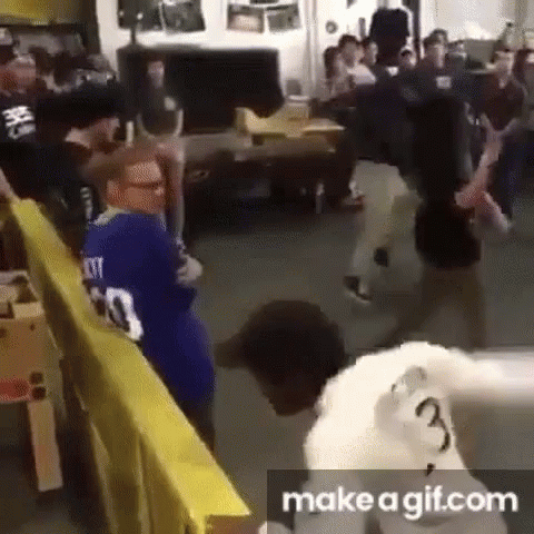 A Group Of People Are Standing Around A Table In A Room With A Yellow Barrier . GIF