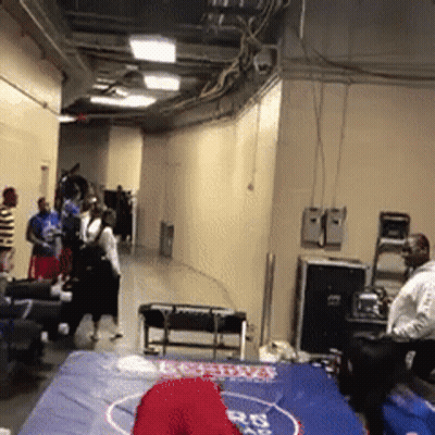 A Group Of People Are Standing Around A Wrestling Mat With A Red Hat On It That Says Boston GIF