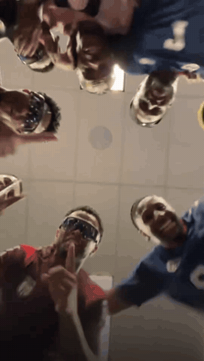 A Group Of People Are Standing In A Circle Looking Up At The Camera . GIF