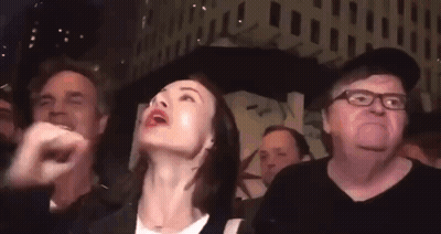 A Group Of People Are Standing In A Crowd And Looking Up At Something . GIF