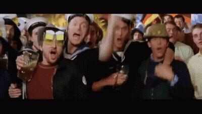 A Group Of People Are Standing In A Crowd Holding Glasses Of Beer And Wearing Helmets . GIF