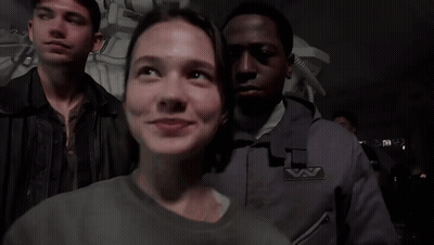A Group Of People Are Standing In A Dark Room And One Of Them Has A Badge That Says ' A ' GIF