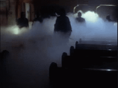 A Group Of People Are Standing In A Dark Room Surrounded By Smoke . GIF