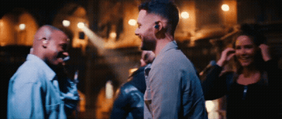 A Group Of People Are Standing In A Dark Room Talking GIF