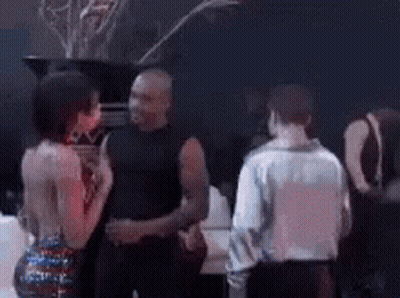 A Group Of People Are Standing In A Dark Room Talking To Each Other GIF