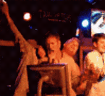 A Group Of People Are Standing In A Dark Room With A Sign That Says Tailgate GIF